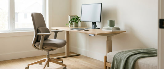 A bright, minimalist home office setup featuring an ergonomic chair, height-adjustable desk, and correctly positioned monitor in soft natural light.