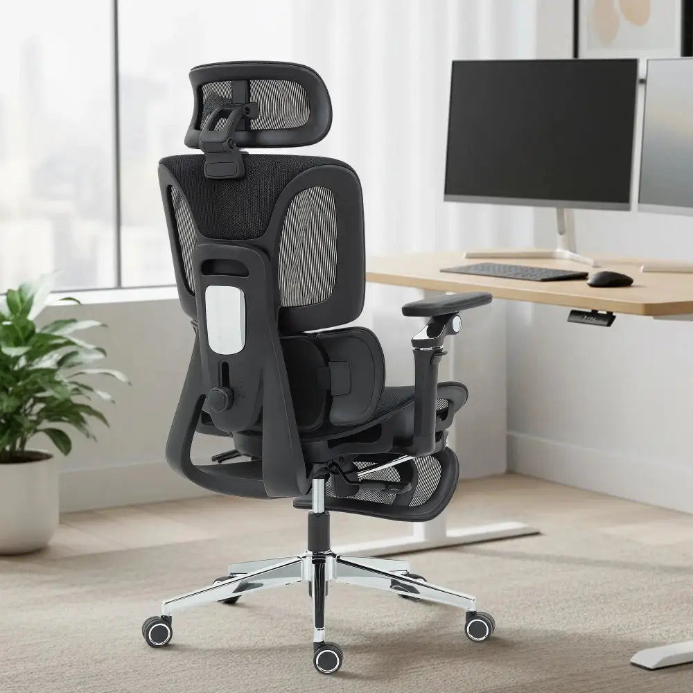 Ergonomic high-back desk chair with separated backrest and headrest, grey mesh, chrome base in a home office.